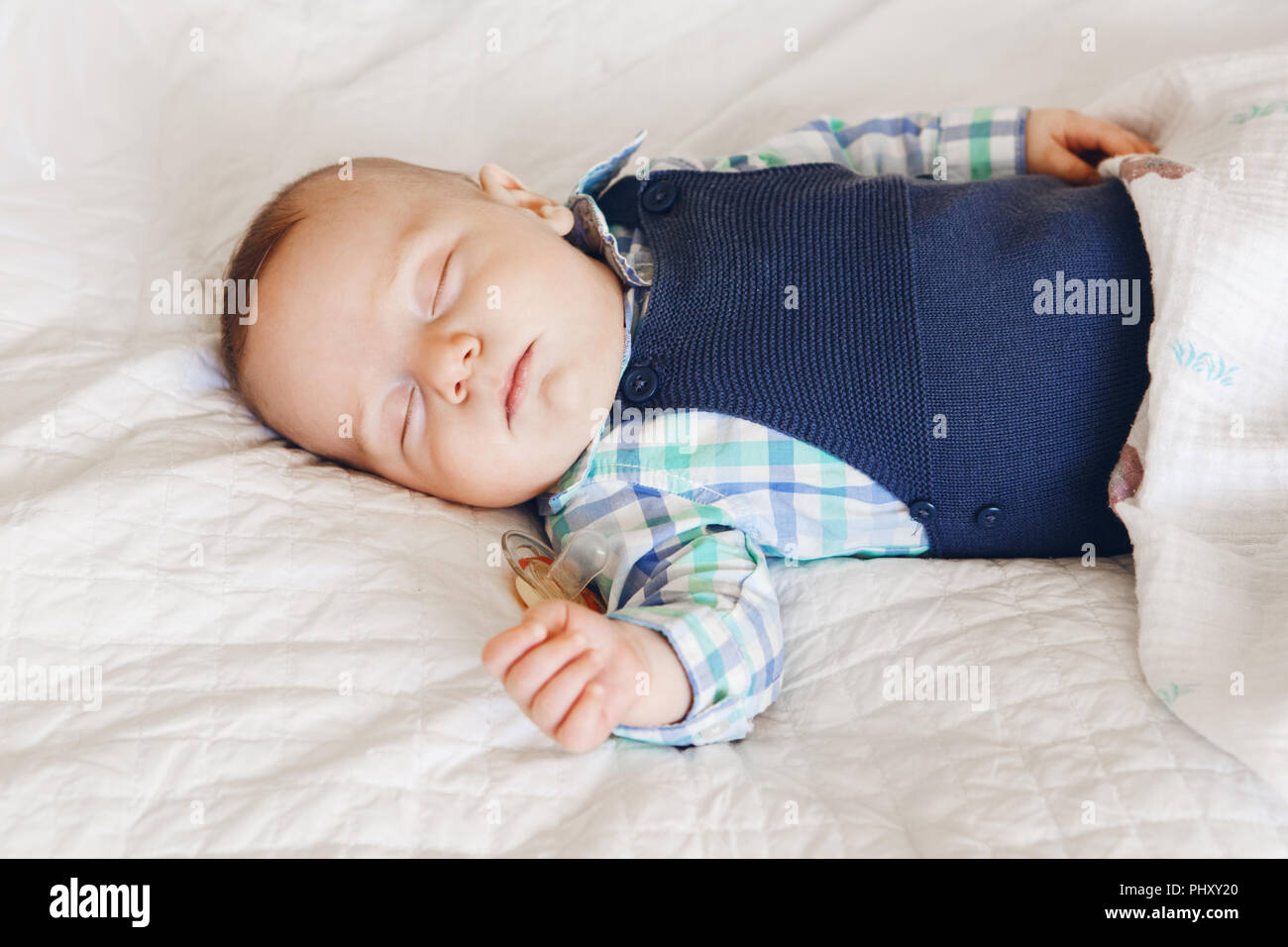 Porträt einer cute adorable White kaukasische Baby neugeborenen Jungen Mädchen schlafen Träumen mit schnuller Schnuller im Mund, das Tragen von T-shirt Body, liegend auf dem Bett Stockfoto
