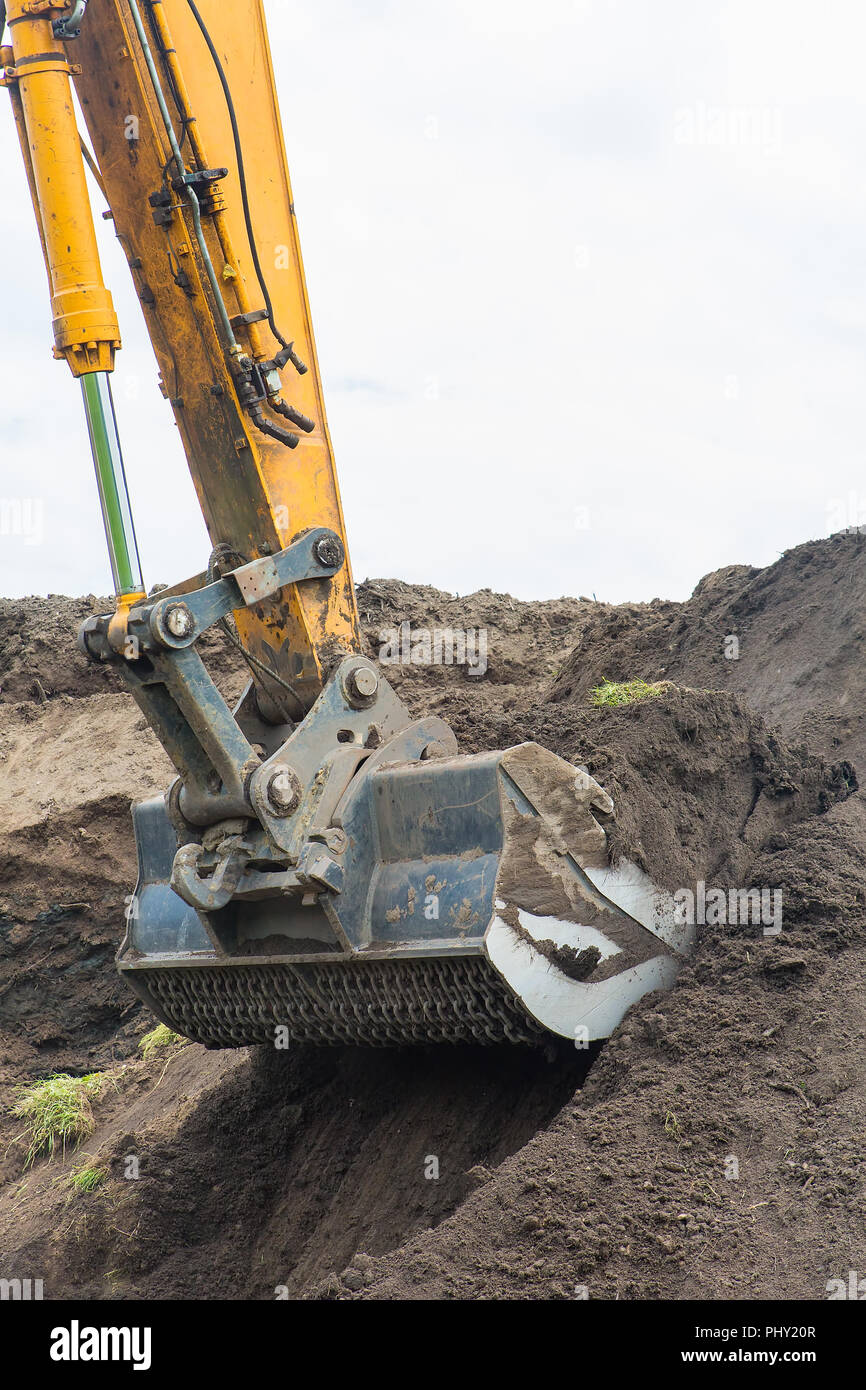Bagger gräbt bis Boden von sandigen Hügel Stockfoto