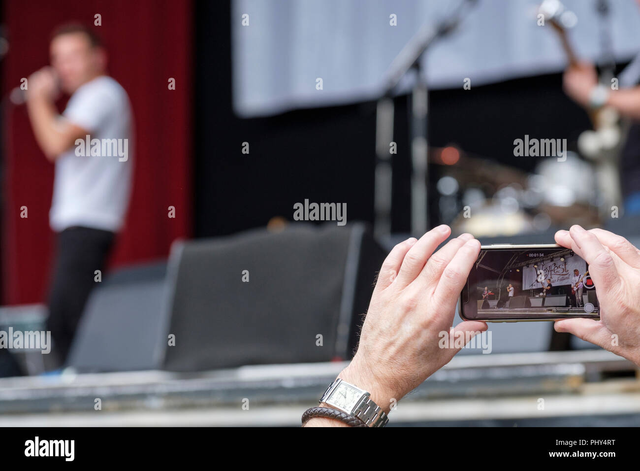 Person, die ein smart phone die Leistung der Musiker an einem Musik Festival aufzeichnen. Stockfoto