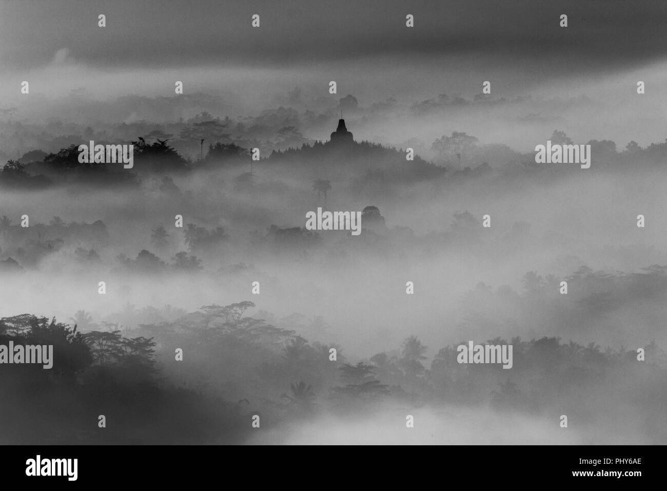 Silhouette des Borobudur-Tempels umgeben von Nebel und Wald in Schwarz-Weiß-Fotografie Stockfoto