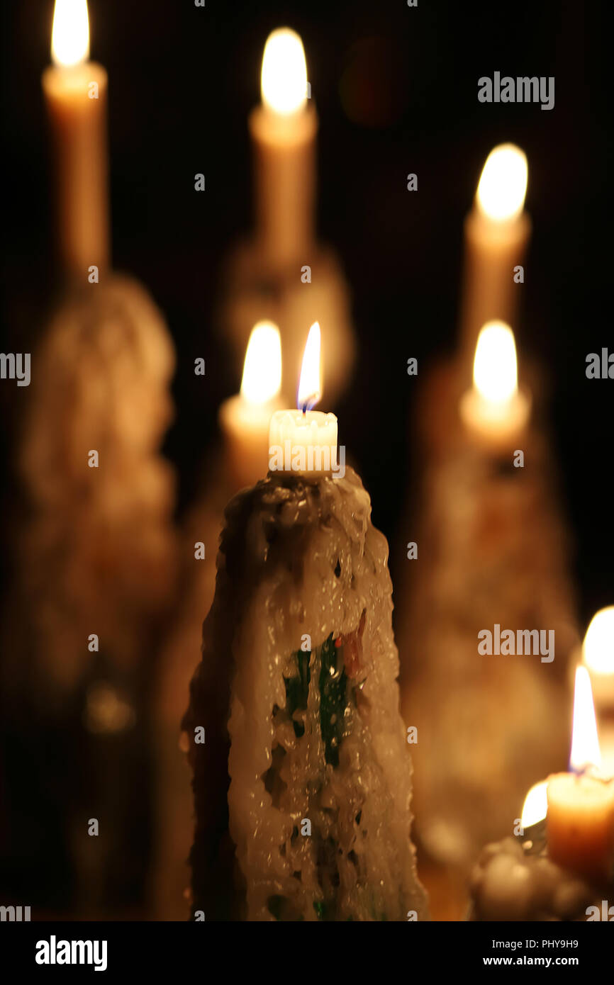 Brennende Kerzen in der Dunkelheit, geschmolzene Wachs, Kerze Flamme. Weihnachten, Neujahr Grußkarte, Allerheiligen, All Hallows Eve, Kirche, Religion, Glauben, Urlaub, magisch, Wintermärchen. Stockfoto
