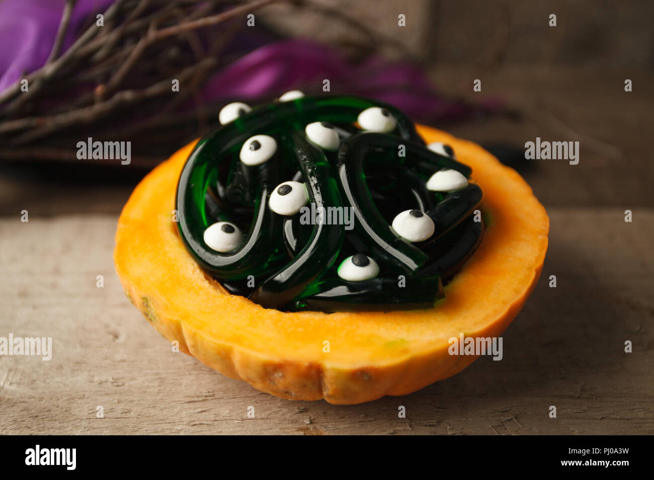 Kürbis und Gummibärchen Worms mit Augen candy auf Holz- Hintergrund. Halloween dekorativen Hintergrund mit Kopie Raum Stockfoto