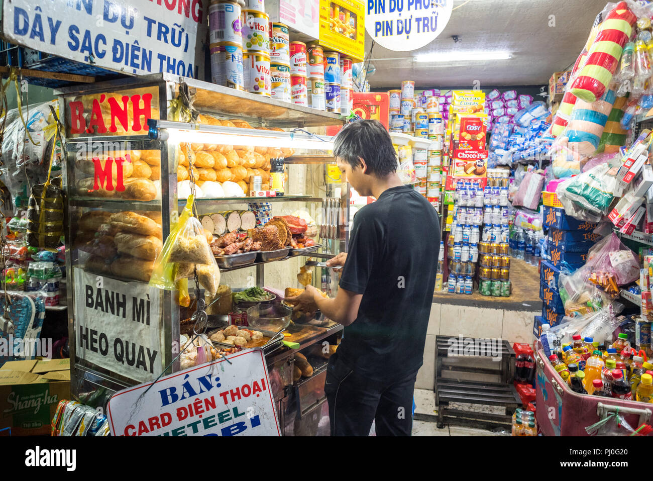 Ho Chi Minh City, Vietnam - Mai 1, 2018: Junger Mann kocht Banh MI mit Zutaten (Brot & Sorten Fleisch) aus einer Street Food Warenkorb in der Straße in der Nacht. Stockfoto