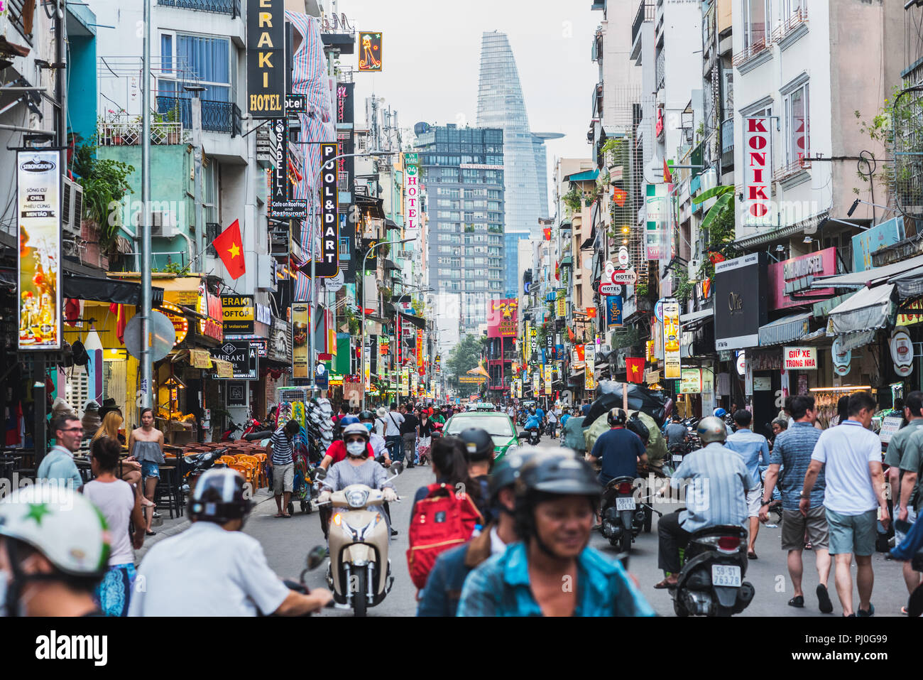 Ho Chi Minh, Vietnam: Bui Vien Straße mit zahlreichen Hotel, Bar und Shop Schilder, mit Menschen & Bikes mit Blick auf bitexco Financial Tower überfüllt. Stockfoto