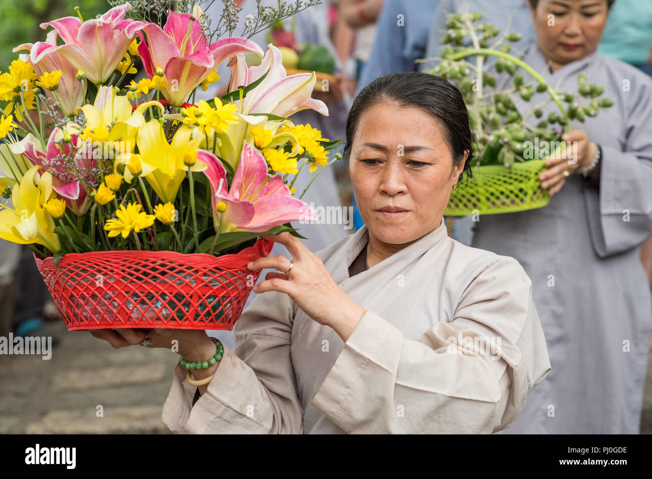 Nha Trang, Vietnam - 5. Mai 2018: Eine Frau mit einem Korb mit Blumen beteiligt sich an der Prozession der Feier von Po Nagar Tempel. Stockfoto