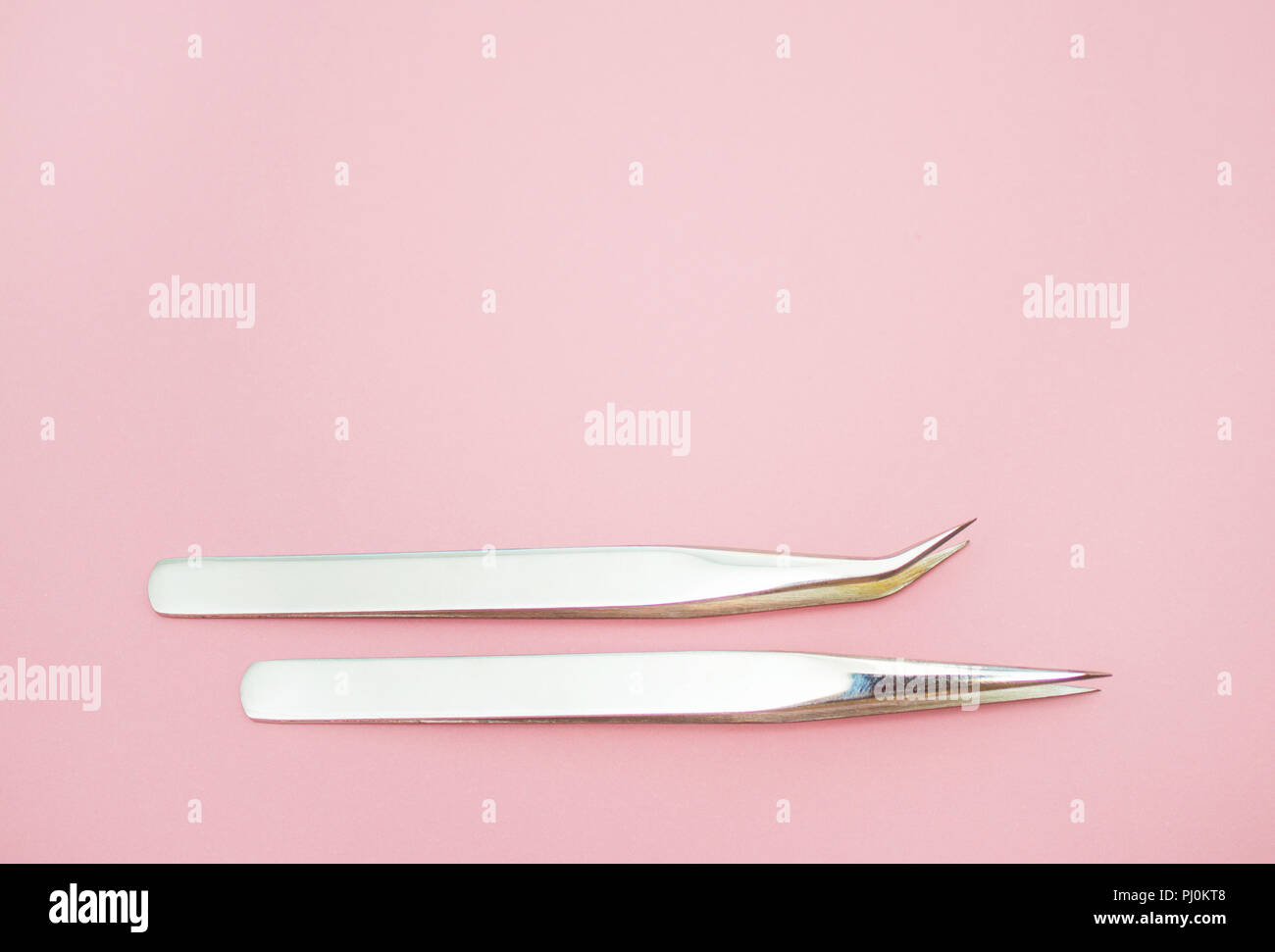 Beauty und Fashion Concept - Werkzeuge für Eyelash Extension Verfahren. Zwei Pinzette auf rosa Hintergrund. Copyspace mockup Stockfoto