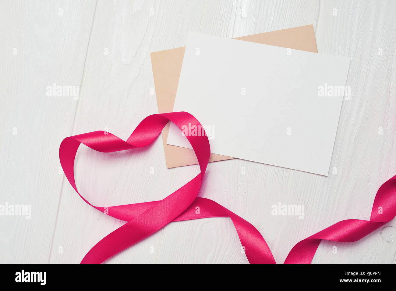 Herz aus roten Band mit Blatt Papier mit weißen Holzmöbeln Hintergrund. Romantische Liebe Konzept. Valentines Tag Hintergrund für Geburtstag, Urlaub, Party, w Stockfoto
