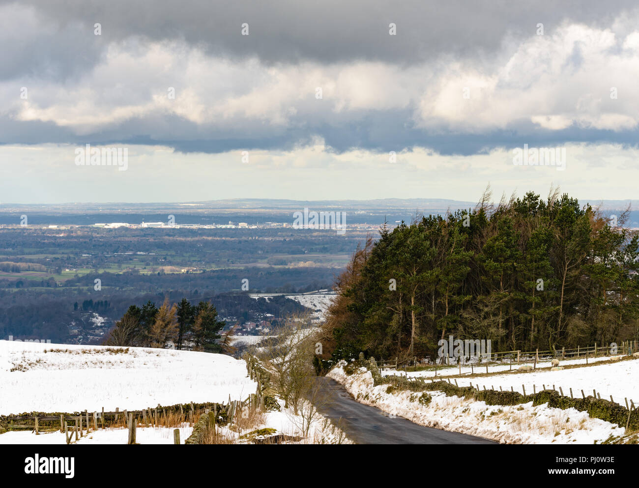Weit weg winterlicher Blick auf Manchester Airport von Rainow in Macclesfield, zeigt ein Flugzeug nähert sich Stockfoto