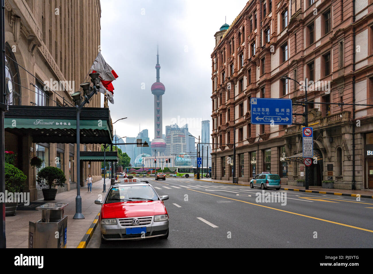 Ein Taxi wartet draussen das Fairmont Peace Hotel in Shanghai, mit einem atemberaubenden Blick auf den Oriental Pearl Tower in den Rücken fallen. Stockfoto