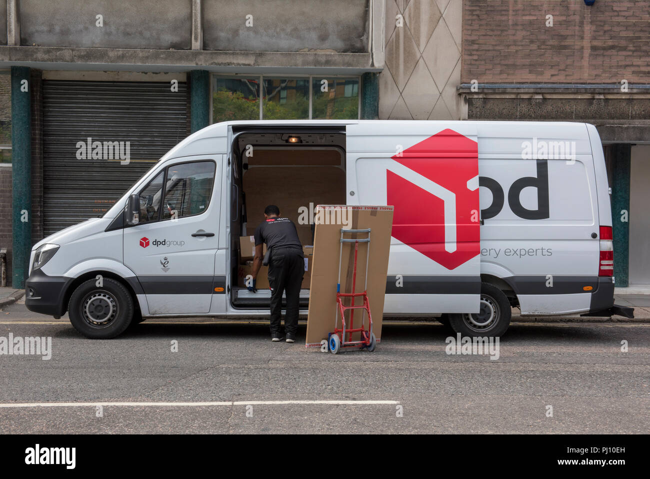 Ein DPD Parcel Distribution und Lieferung Treiber liefern ein großes Paket  an eine Geschäftsadresse in Central London Stockfotografie - Alamy
