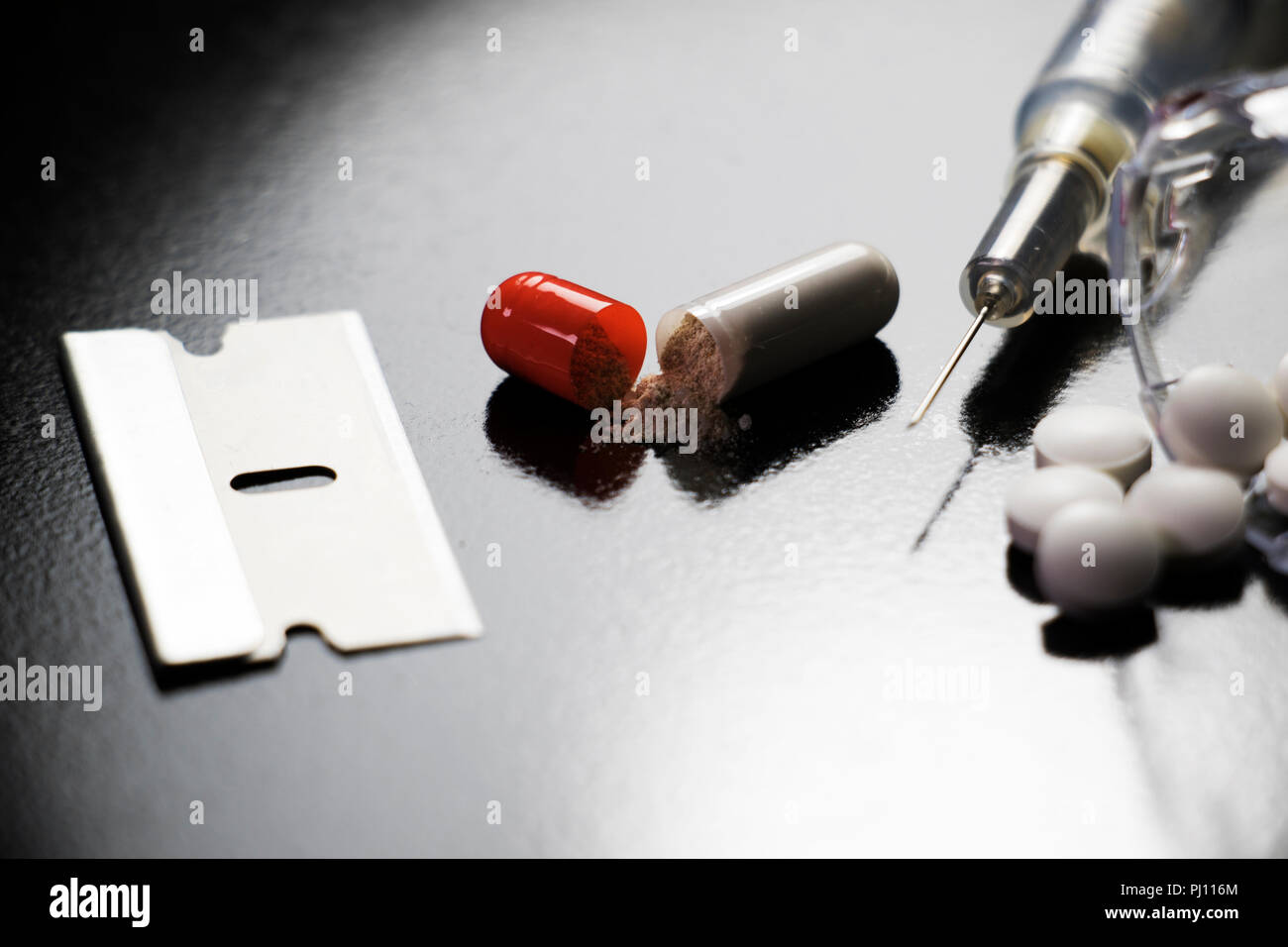Droge-utensilienien auf schwarzem Hintergrund. Pillen, Nadeln, Rasierklingen. Narkotische Objekte Drogenmissbrauch und Drogenabhängigkeit. Stockfoto