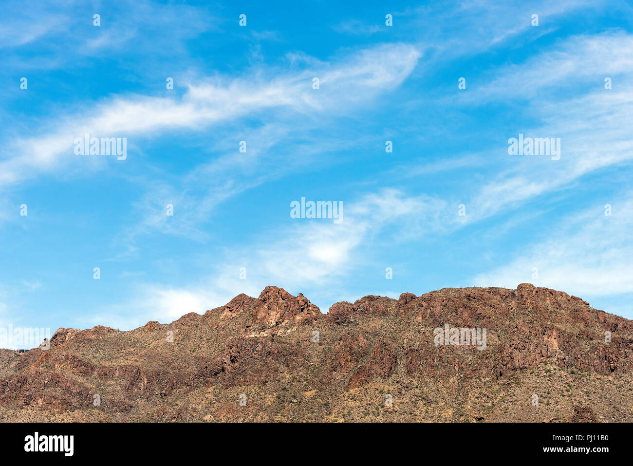 Karge braune felsigen Bergspitzen unter einer leichten blauen Himmel mit flauschigen weissen Wolken. Stockfoto