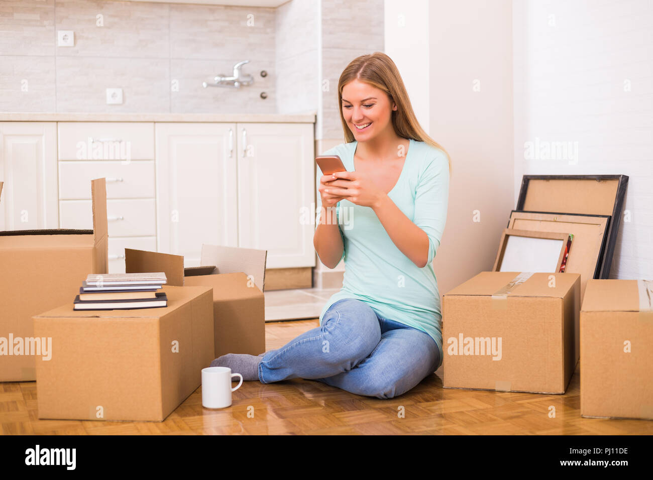 Schöne Frau mit Telefon, während Sie in Ihre neue Wohnung. Stockfoto