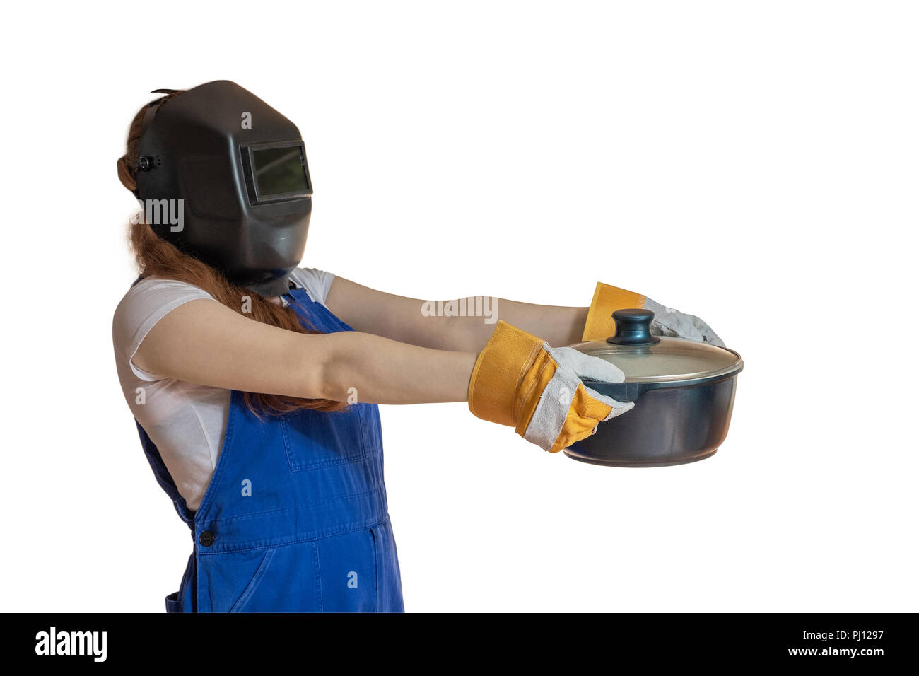 Das Mädchen in der Arbeitskleidung und Schweiß-Maske hält eine Pfanne in der Hand nach vorne verlängert. Stockfoto