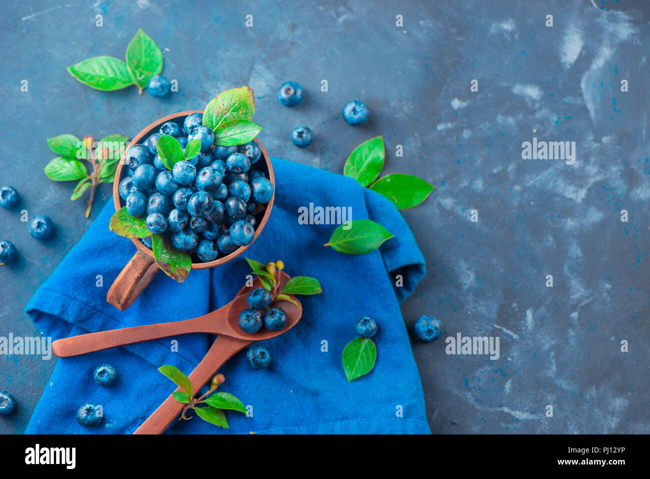 Handgefertigte Keramik Tasse mit Heidelbeeren. Reif und süß Sommer Beeren auf einen konkreten Hintergrund. Natürliche Schönheit, blau und grau Palette, kopieren Raum Stockfoto