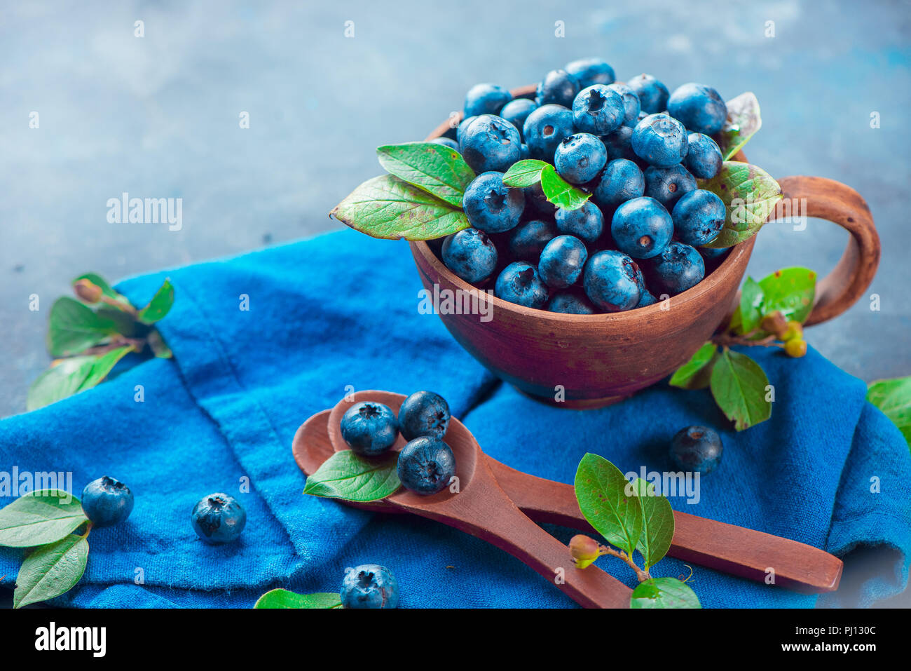 Handgefertigte Keramik Tasse mit Heidelbeeren. Reif und süß Sommer Beeren auf einen konkreten Hintergrund. Natürliche Schönheit, blau und grau Palette, kopieren Raum Stockfoto