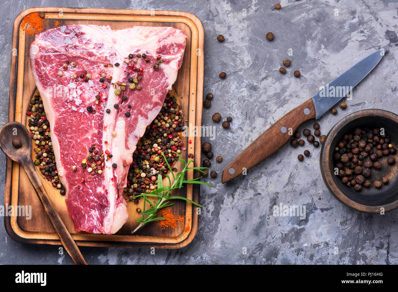 Raw marmoriertes Fleisch Steak, Pfeffer auf alten hölzernen Brett. Beef Rib Eye Steak Stockfoto