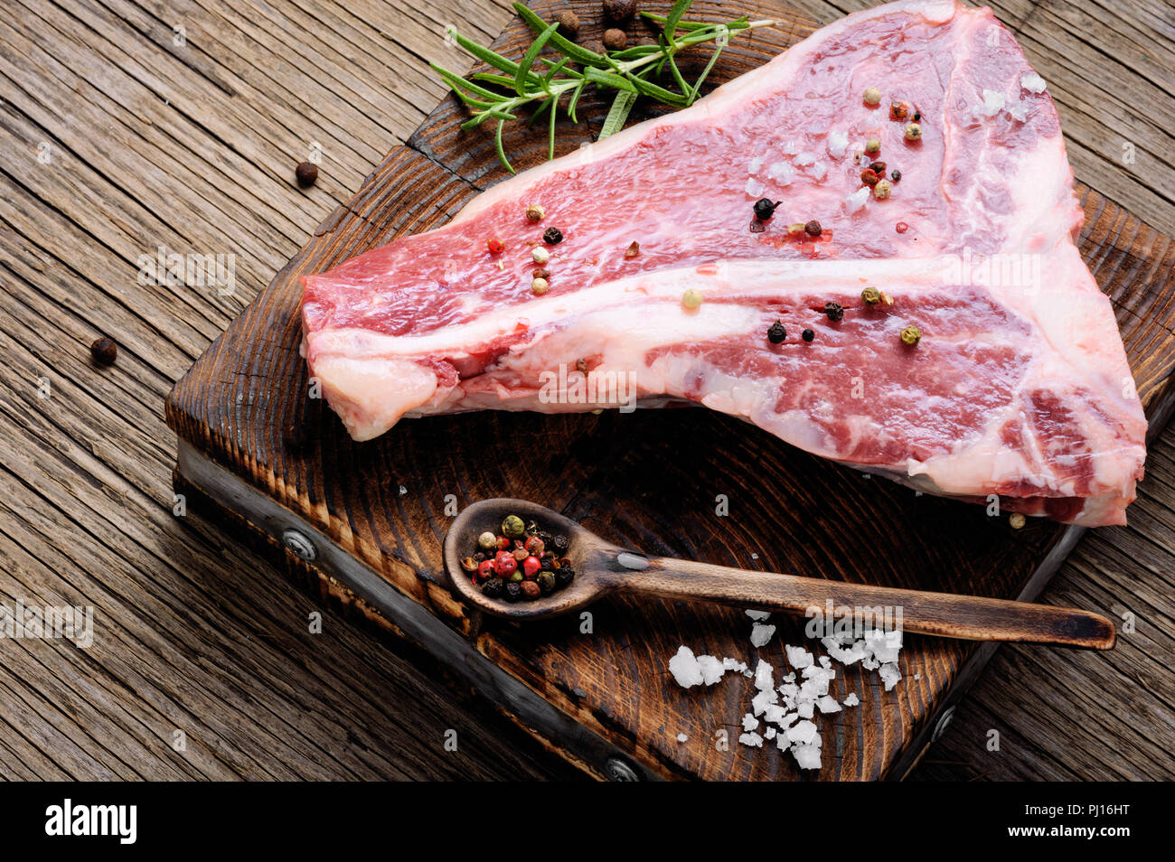 Raw marmoriertes Fleisch Steak, Pfeffer auf alten hölzernen Brett. Beef Rib Eye Steak Stockfoto