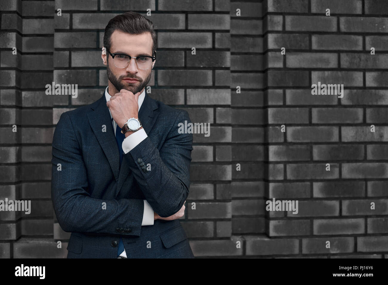 Porträt eines lächelnden schönen Geschäftsmann mit über Betonwand verschränkten Armen Stockfoto