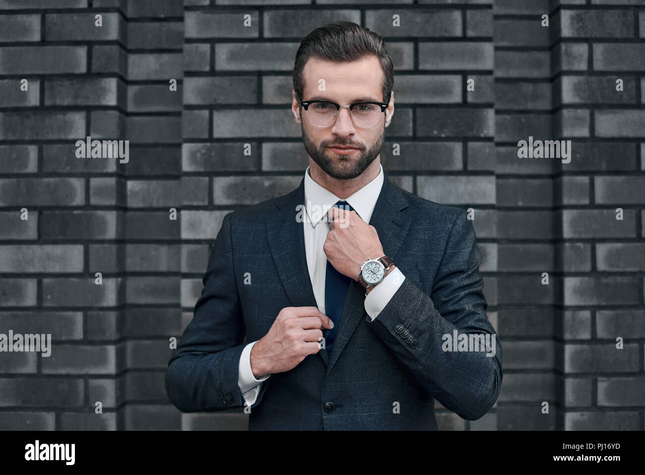 Porträt eines lächelnden schönen Geschäftsmann mit über Betonwand verschränkten Armen Stockfoto