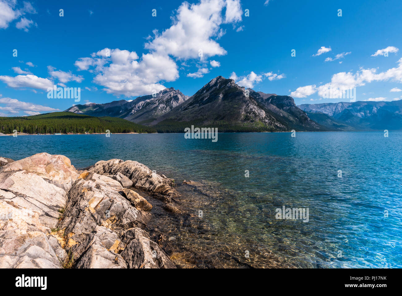 Tief blauen Himmel, weiße Wolken und das blaue Wasser des Lake Minnewanka durch die Kanadischen Rockies. Stockfoto