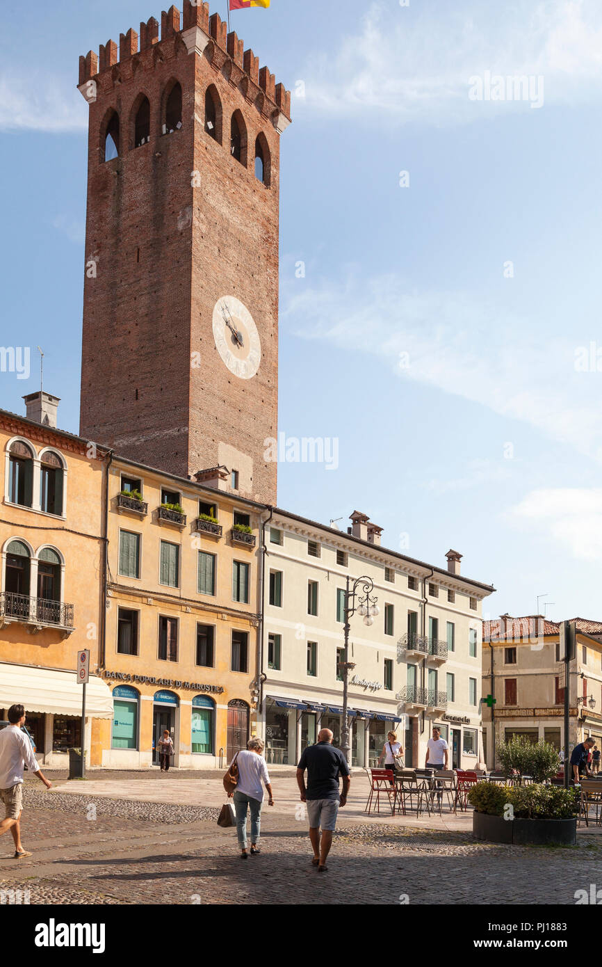 Mittelalterlichen Stadtturm, Piazza Garibaldi, Bassano del Grappa, Vicenza, Italien im frühen Morgenlicht mit Einheimischen zu Fuß durch das Quadrat Stockfoto