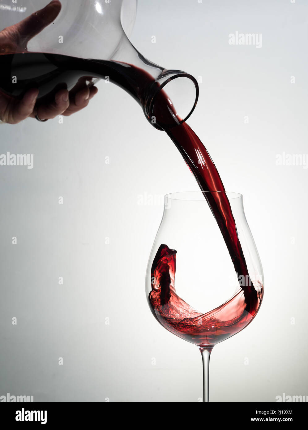Rotwein wird in ein Glas gegossen. Stockfoto