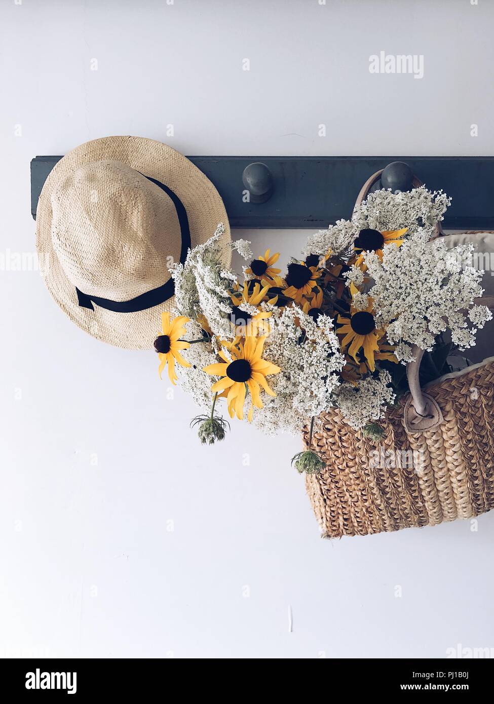 Die Zustellung der Blumen in einem Korb hängen an einer Garderobe mit einem Hut Stockfoto