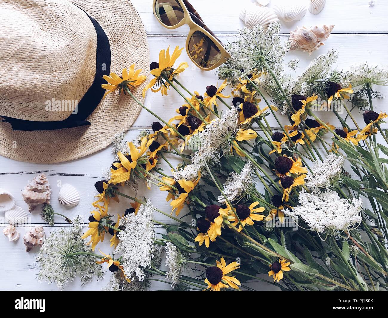Wildblumen, Stroh Hut, Sonnenbrille und Muscheln Stockfoto