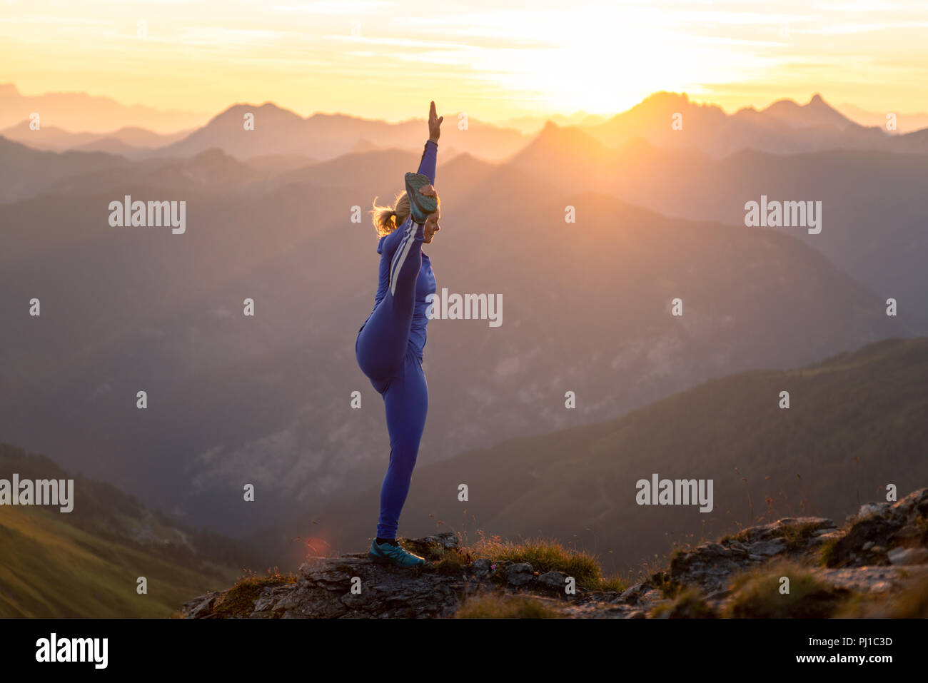 Frau tun verlängerte Hand-zu-großzehe Pose auf Bergrücken bei Sonnenaufgang, Gastein, Salzburg, Österreich Stockfoto