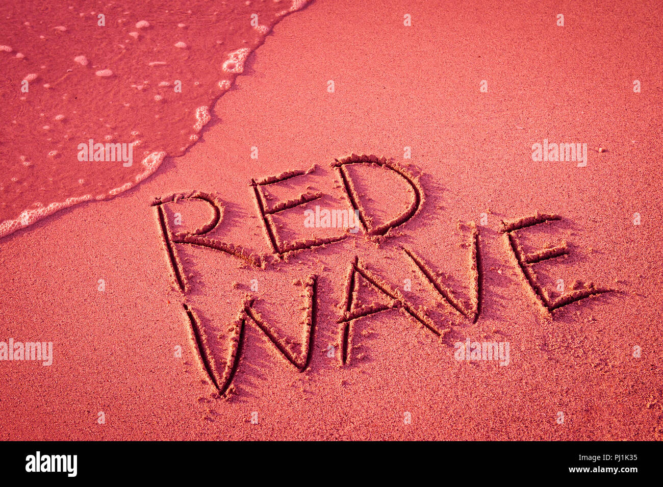 'ReD WELLE' in den Sand geschrieben am Strand mit Meerblick Waschmaschine bis zum Ufer. Stockfoto