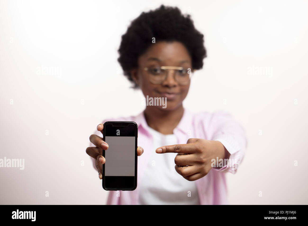 Schauen Sie bitte hier. Angenehme lächelnde Frau Werbung eine trendige smart phone Stockfoto