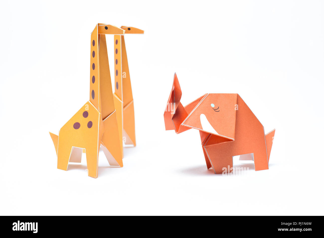 Drei origami Tiere stehen auf einem weißen Hintergrund, zwei Giraffen und ein Elefant Stockfoto