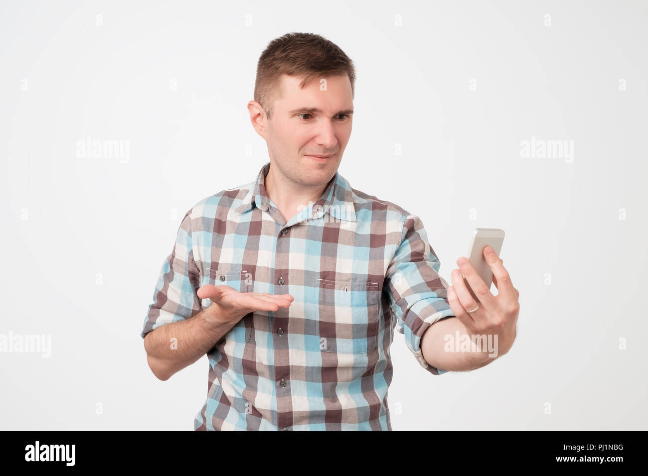 Portrait von Yong Mann an seinem Smartphone in Verwirrung auf der Suche Stockfoto