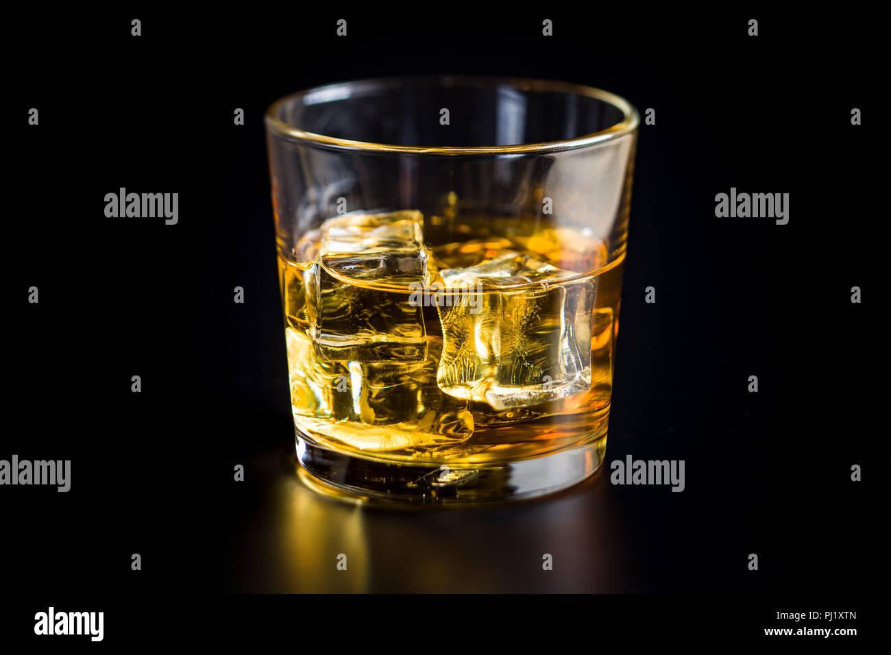 Glas alkoholische Getränke mit Eiswürfeln auf Schwarz. Whiskey in Glas. Stockfoto