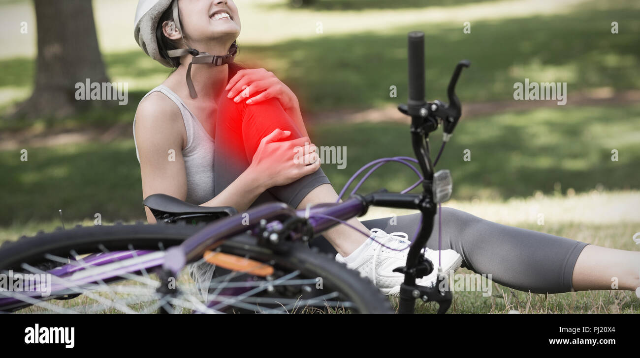 Das zusammengesetzte Bild der weiblichen Radfahrer mit verletzten Bein im Park sitzen Stockfoto