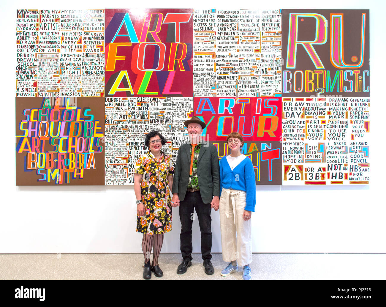 Royal Academy, London, UK. 4. September, 2018. Gefeierten Künstler Bob und Roberta Smith RA (Pseudonym erstellt von dem Künstler Patrick Brill) erscheint neben seiner neuen Anzeige an der Royal Academy. Das Geheimnis eines guten Lebens ist das erste Display, das durch einen Königlichen Akademiker im neu eröffneten Ronald und Rita McAulay Galerie, ein Ort, der für Standort-spezifischen Installationen durch Königlichen Akademiker. Foto: Der Künstler mit seiner Frau und seiner Tochter: Links, Künstlerin Jessica Voorsanger und, rechts, artist Etta Voorsanger-Brill. Credit: Malcolm Park/Alamy Leben Nachrichten. Stockfoto