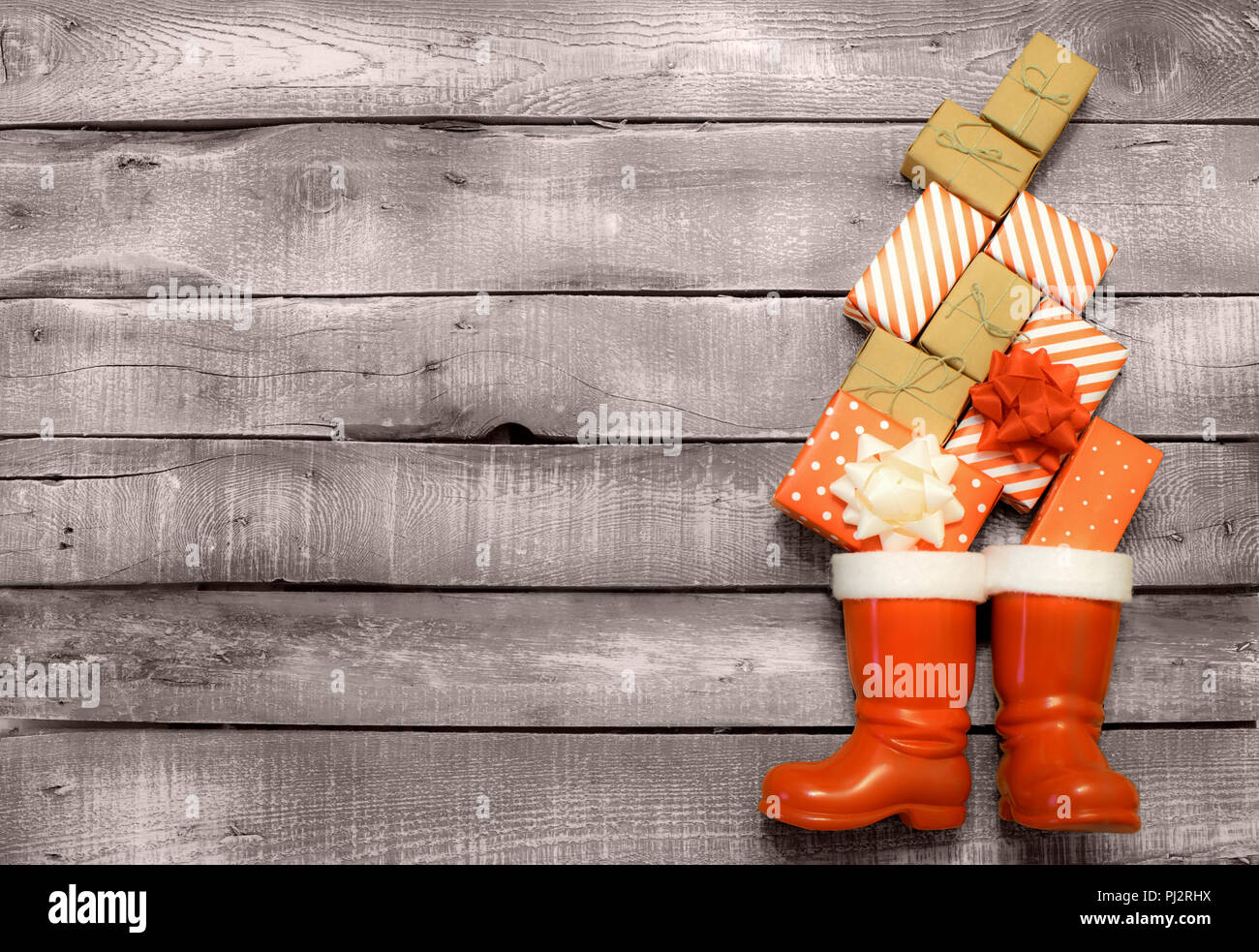 Weihnachten Hintergrund - Rot und Braun Geschenke fallen in Weihnachtsmänner oder Sankt Nikolaus Stiefel auf Grau rustikal Hintergrund Stockfoto