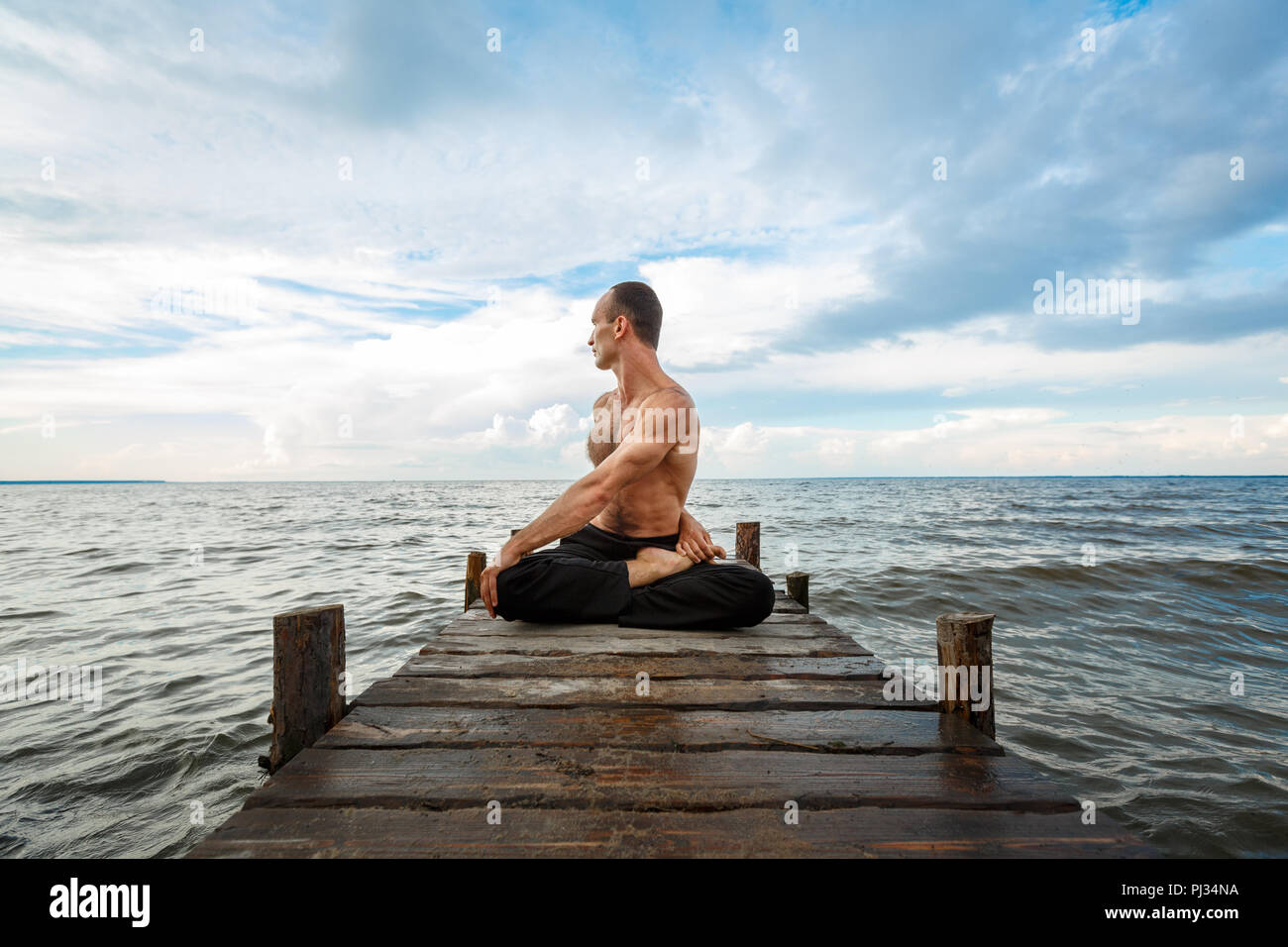 Junge yoga Trainer Yoga Übungen auf einer hölzernen Pier an einem See oder Fluss Ufer. Gesunder Lebensstil Konzept Stockfoto