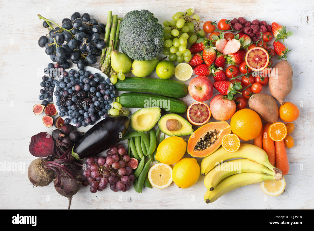 Gesunde Ernährung Konzept, Sortiment von Rainbow Obst und Gemüse, Beeren, Bananen, Orangen, Weintrauben, Brokkoli, rote Beete an der aus weissen Tisch in einem Rechteck, Ansicht von oben angeordnet, selektiver Fokus Stockfoto