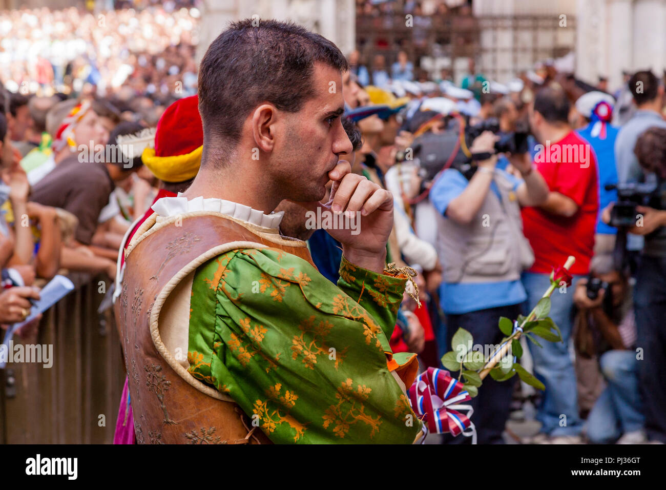 Ein Mann aus der Selva (Wald) Contrada wartet auf die Zuordnung der Pferde Zeremonie in der Piazza Del Campo, Palio di Siena, Siena, Italien zu beginnen. Stockfoto