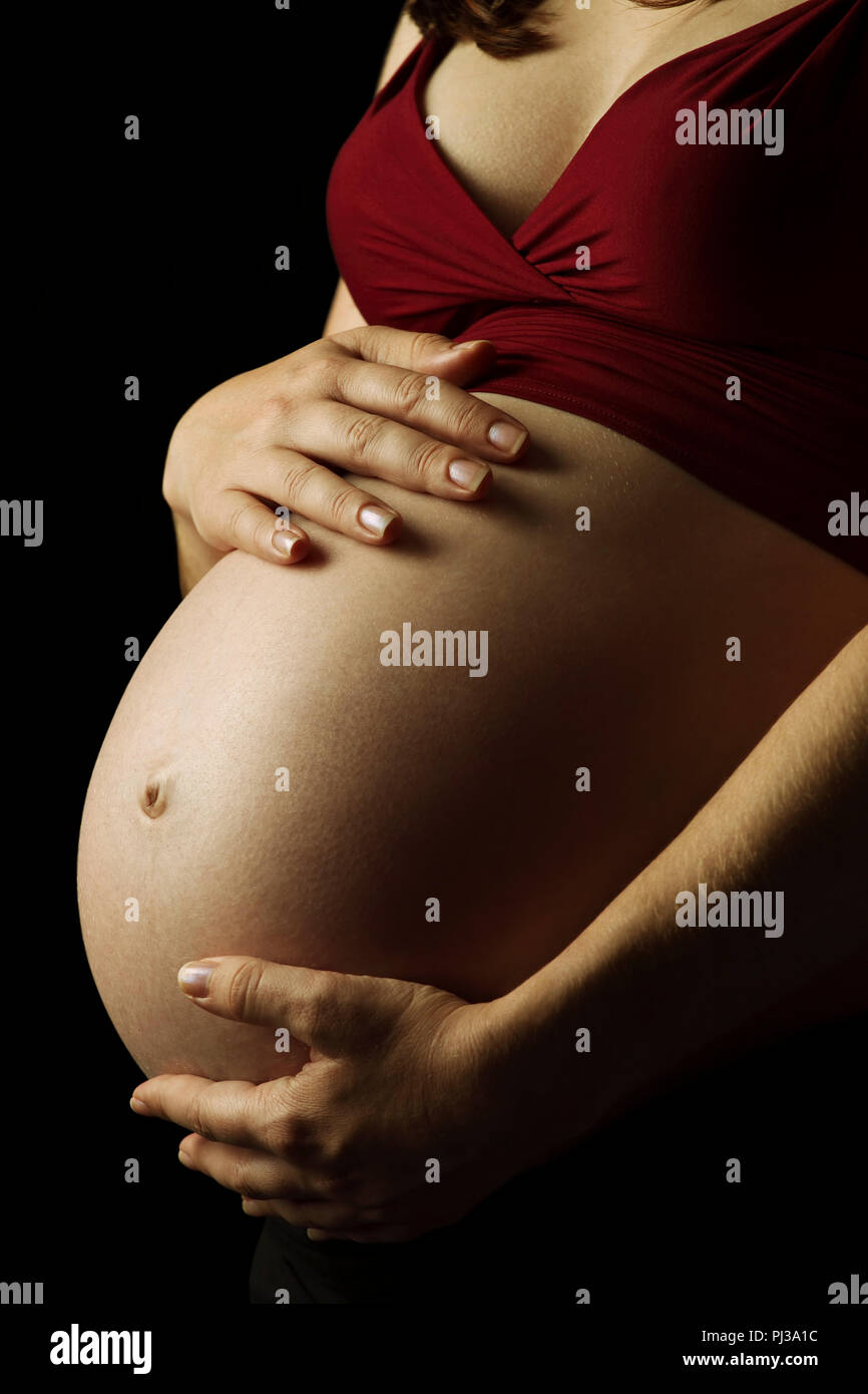 Foto einer schwangeren Frau mit ihren Händen auf den Bauch. Stockfoto