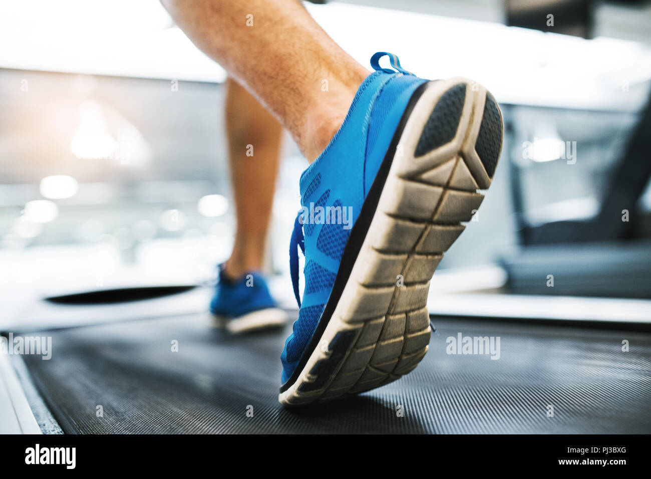 Die Füße des jungen Mannes im Fitnessraum mit Laufband. Stockfoto