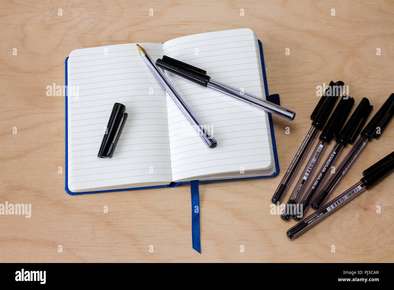 Leere gesäumt Notebook mit einigen schwarzen Kugelschreiber Kugelschreiber auf einem hellen Hintergrund Stockfoto