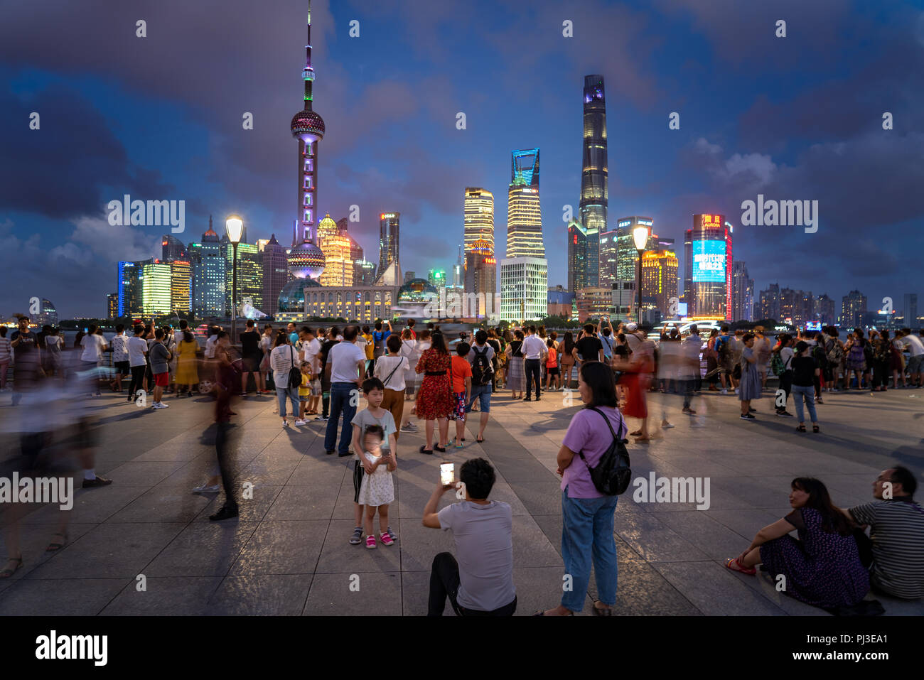 Familie nimmt ein Foto entlang der Bund in Shanghai, China, mit der Skyline im Hintergrund und riesige Menschenmengen entlang der Promenade. Stockfoto