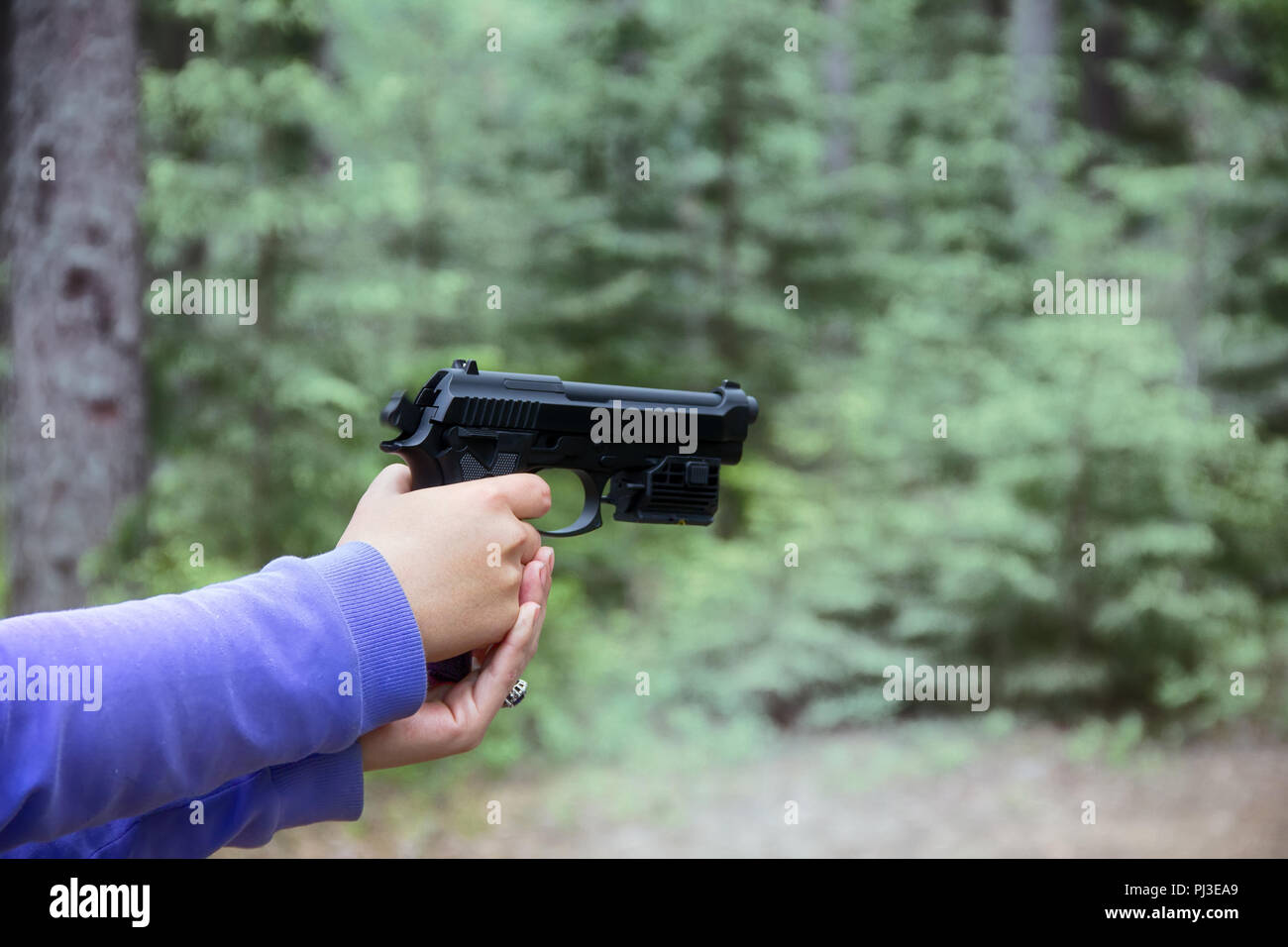 Frau schießt aus Luftgewehr Pistole (schwarz Air Gun) im Wald. Hände und Arme sichtbar, verschiedene Kamerawinkel Stockfoto