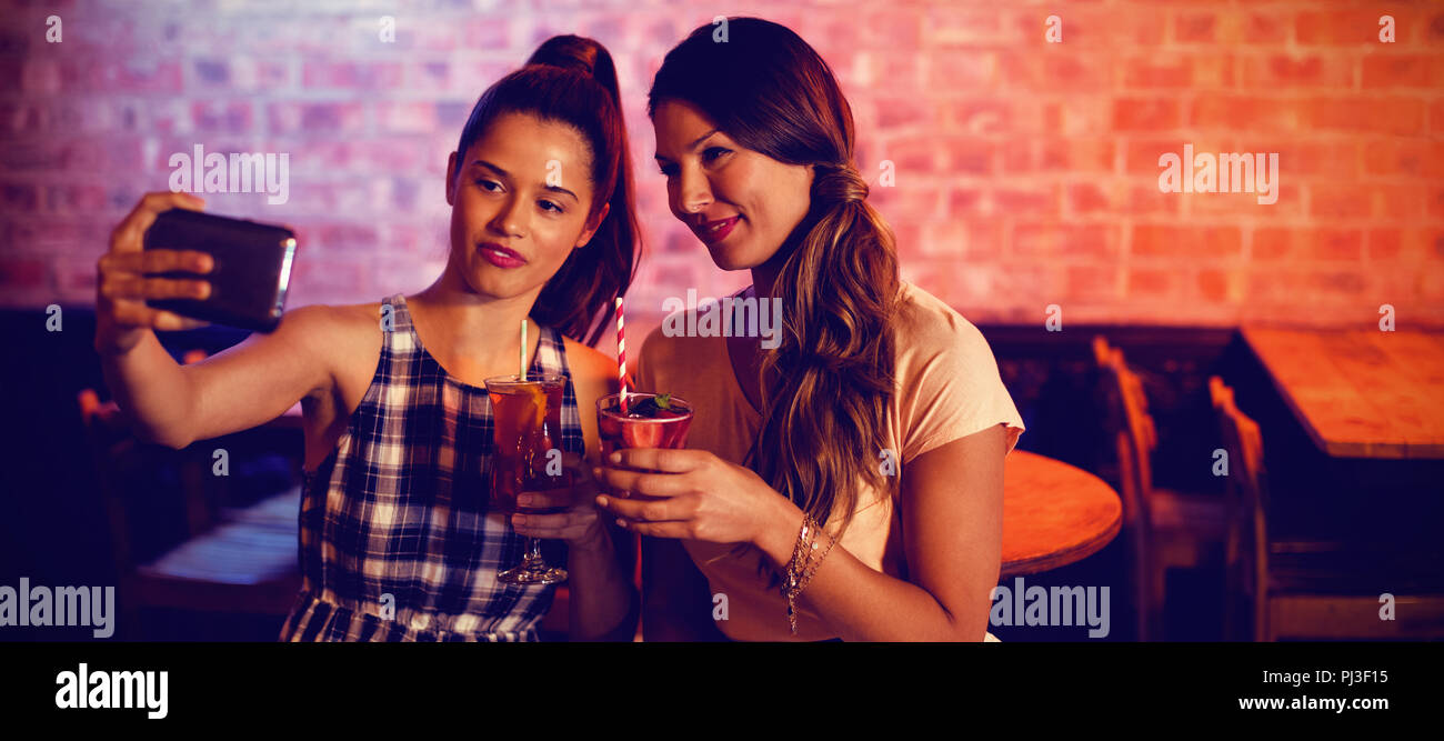Junge Frauen, die ein selfie während mit Cocktail Drinks Stockfoto