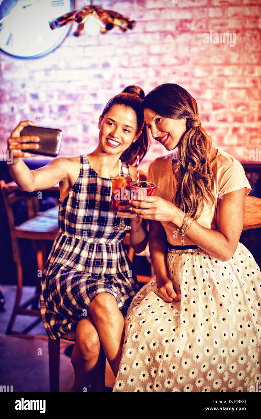 Junge Frauen, die ein selfie während mit Cocktail Drinks Stockfoto