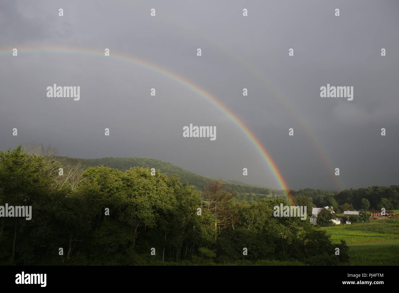 Doppelter Regenbogen über dem Bauernhof Berg Stockfoto