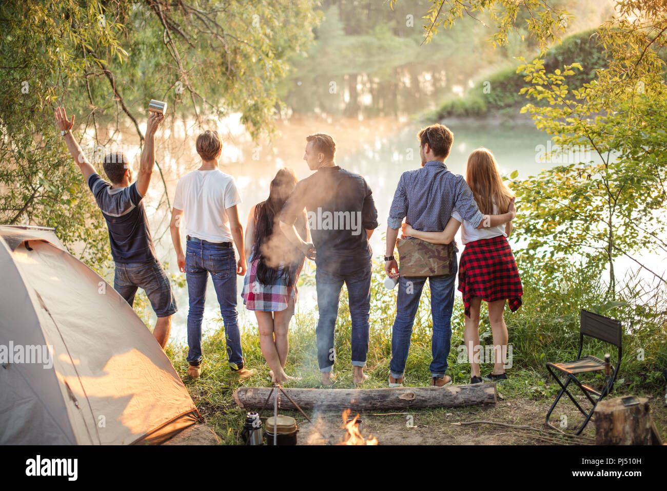 Junge fröhliche Menschen stehen gegen den Sonnenuntergang. Travel Concept Stockfoto